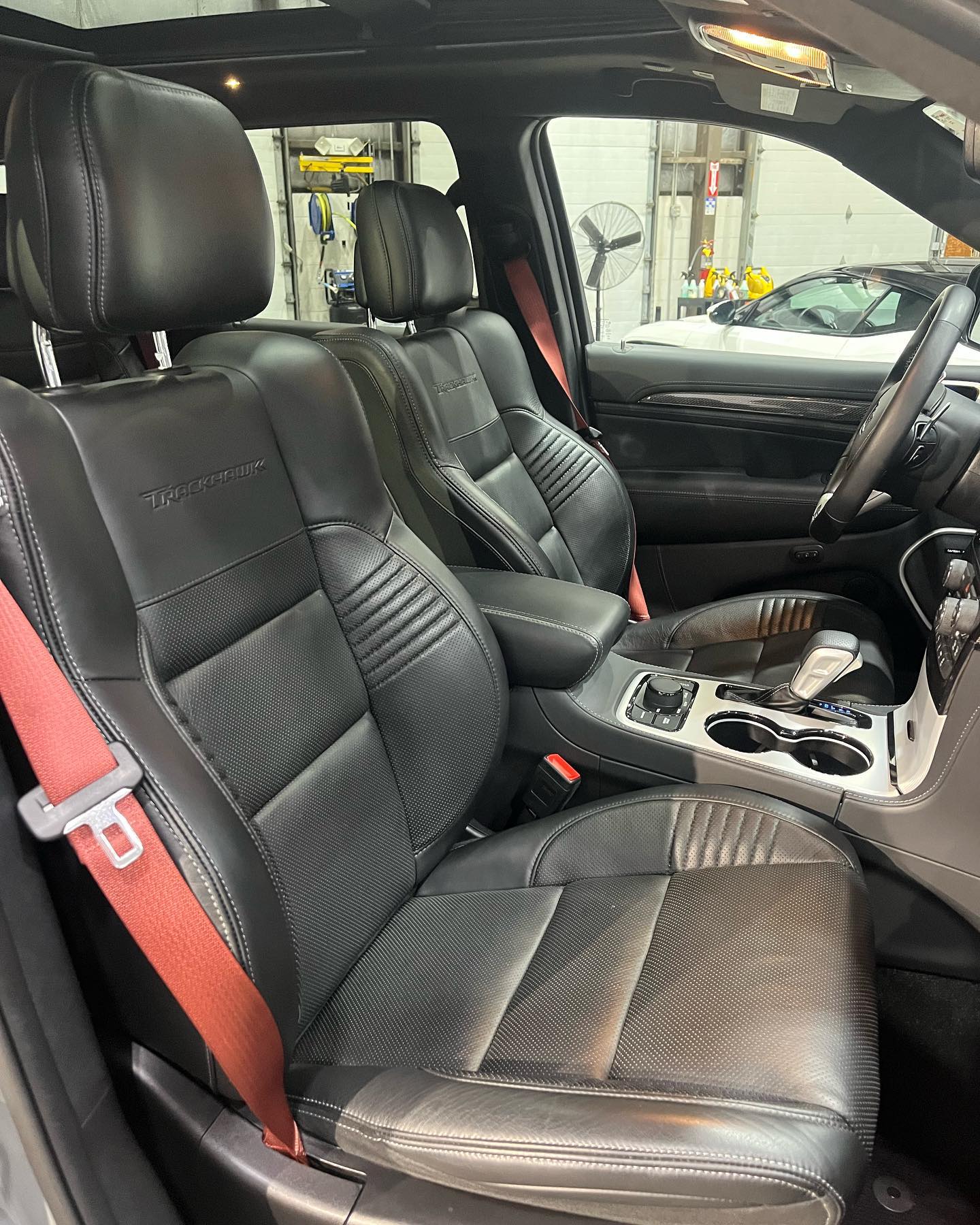 Jeep Grand Cherokee Trackhawk interior with black leather and red seatbelts