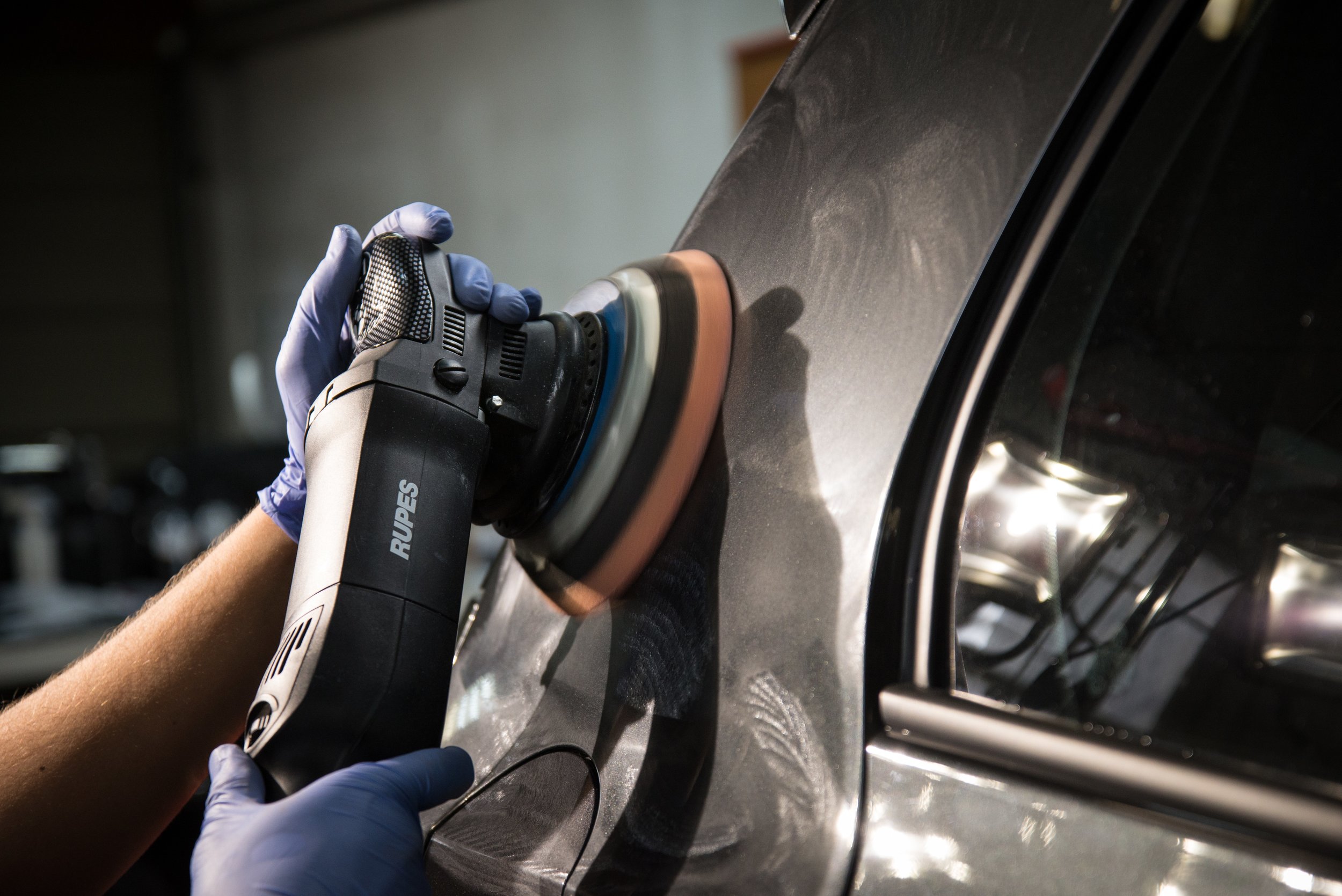 Dual-action polisher mid-pass on a dark metallic panel